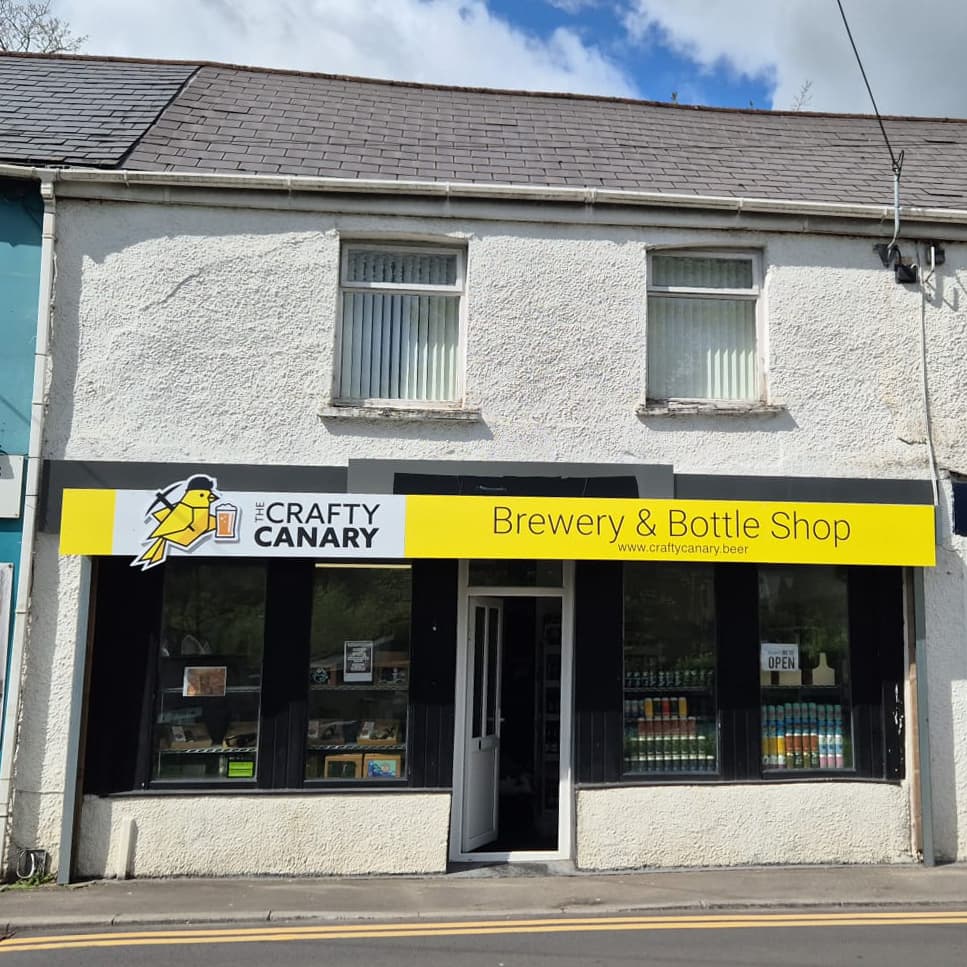 The Crafty Canary shopfront on the High Street in Cwmafan, with a yellow sign reading Brewery and Bottle Shop